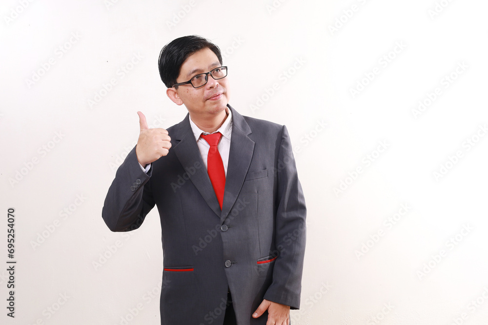 Asian businessman standing while looking sideways and showing thumbs up. Isolated on white Asian businessman standing while looking sideways and showing thumbs up. Isolated on white