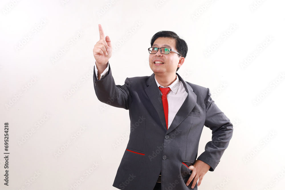 Happy asian businessman standing while pointing above. Isolated on white background Happy asian businessman standing while pointing above. Isolated on white background