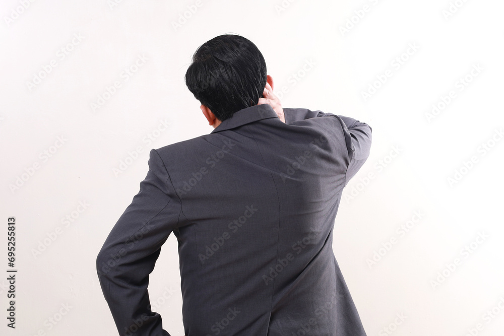 Back view of asian businessman standing while having problem with his neck. Tired concept Back view of asian businessman standing while having problem with his neck. Tired concept