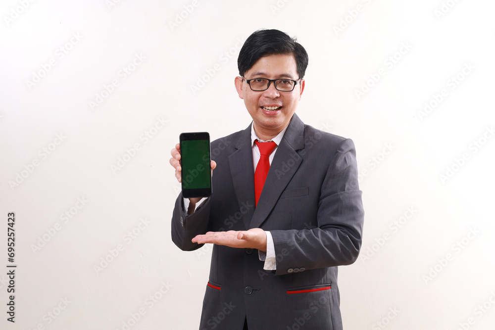 Happy asian businessman standing while presenting blank cell phone display. Isolated on white Happy asian businessman standing while presenting blank cell phone display. Isolated on white