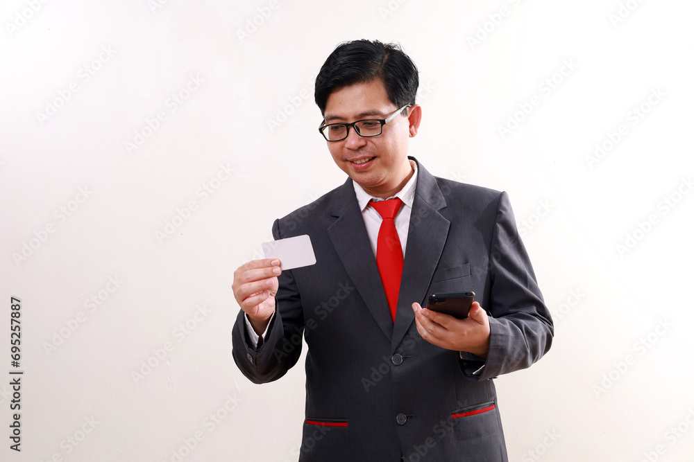 Happy asian businessman holding a cell phone and a blank card. Isolated on white Happy asian businessman holding a cell phone and a blank card. Isolated on white
