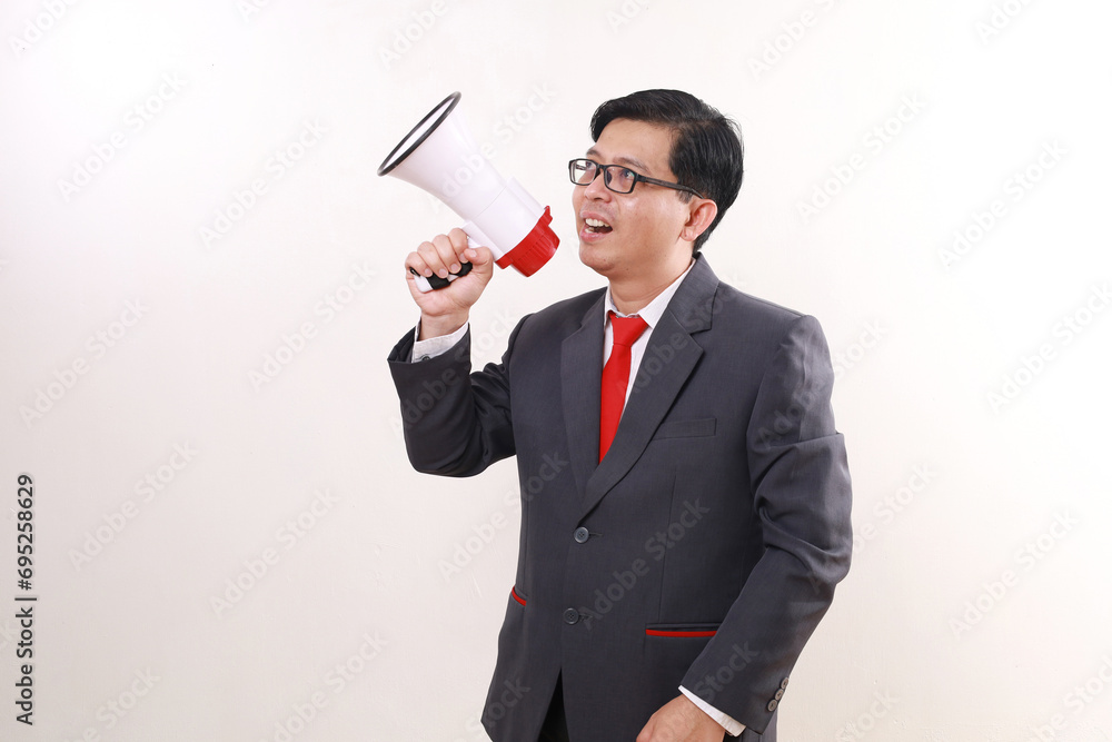 Happy asian businessman looking sideways while holding megaphone. Isolated on white Happy asian businessman looking sideways while holding megaphone. Isolated on white