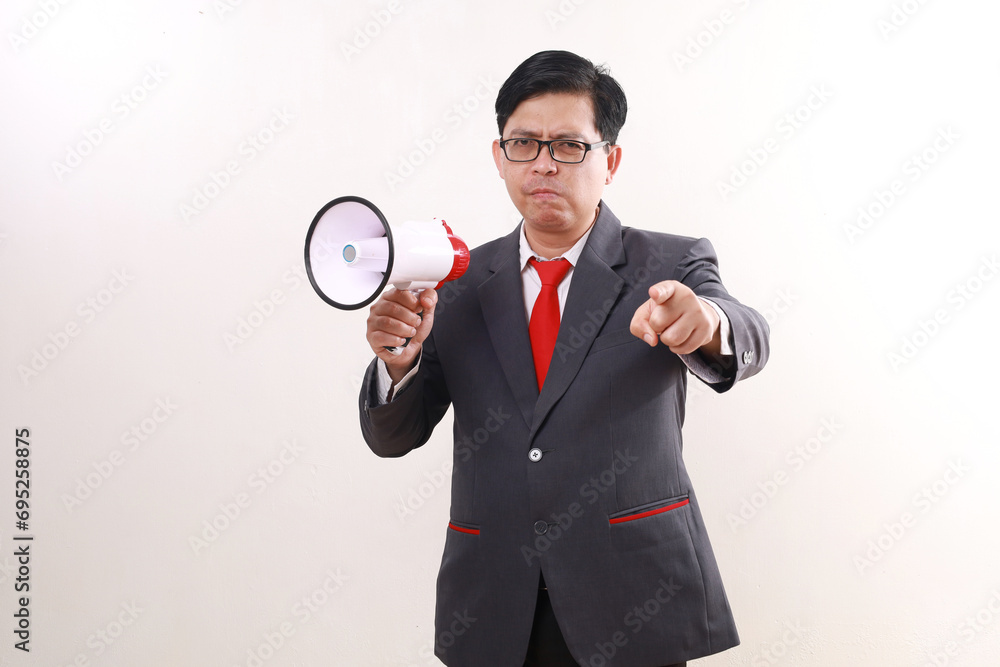 Angry asian businessman shouting using megaphone while pointing at you. Isolated on white Angry asian businessman shouting using megaphone while pointing at you. Isolated on white