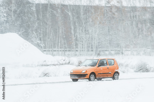 Car on a winter road with a lot of snow and ice. The car is equipped with winter tyres and is creating a splash of snow and water. Winter road trip with a car. Snowy landscape on the highway.