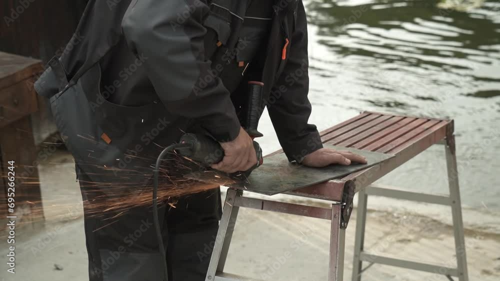 Worker cutting metal tube using an Angle Grinder. Bright sparks and flashes Worker cutting metal tube using an Angle Grinder. Bright sparks and flashes