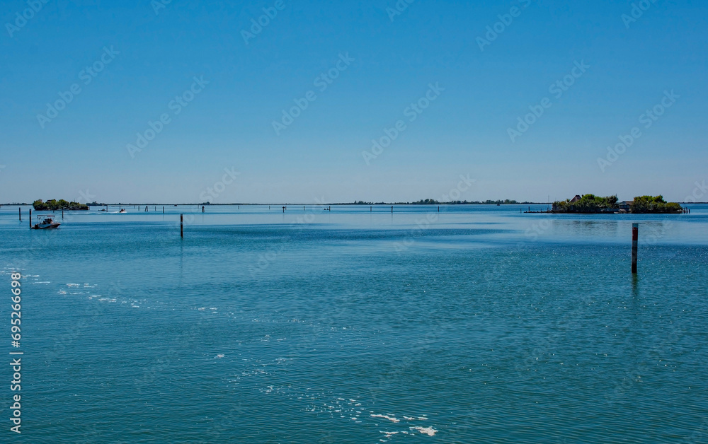 Markers show the edge of a navigable channel in the shallow waters in the Grado section of the Marano and Grado Lagoon in Friuli-Venezia Giulia, north east Italy. August