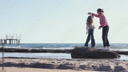 Happy family dancing together on seaside, mom and her little daughter spend happy time together on seashore in winter