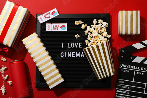 Letter board with text, popcorn, tickets and boxes on red background, top view