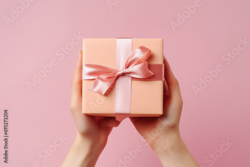 hands holding gift box on pink background. © Neha