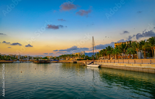 Sunset at Hawana Salalah marina with moored yachts, resorts and palm trees in Oman photo