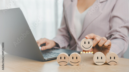 The client's hand picked the happy face smile face icon and five star symbol on wooden cube on table. Customer service evaluation and satisfaction survey concepts.