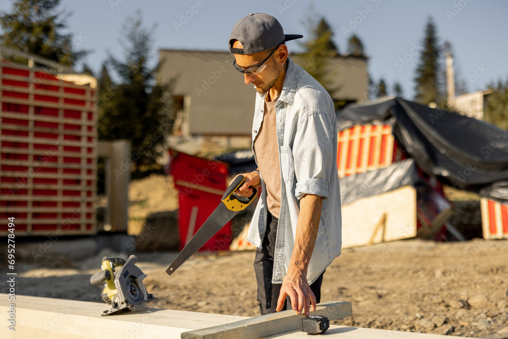 Carpenter works on a construction site, building a frame house in mountains Carpenter works on a construction site, building a frame house in mountains