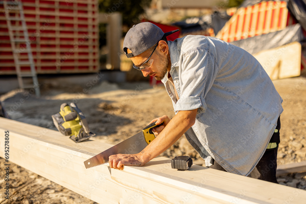 Carpenter works on a construction site, building a frame house in mountains Carpenter works on a construction site, building a frame house in mountains