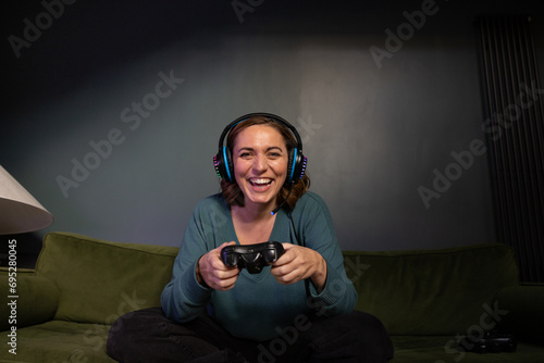 Mid adult female gamer playing at home at night photo