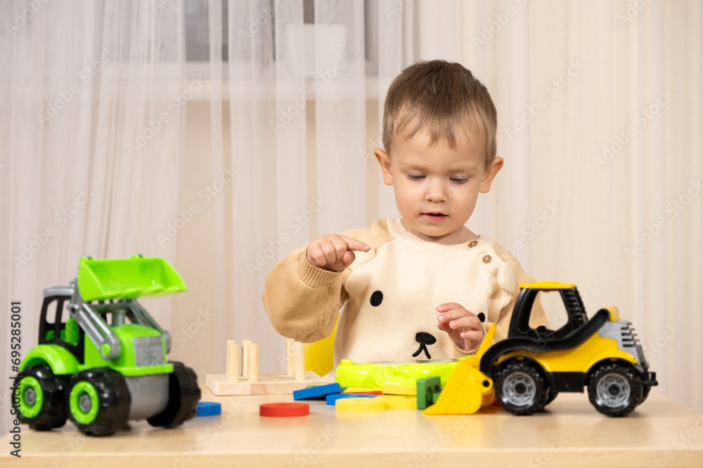 Little cute boy playing with toys while sitting at table Little cute boy playing with toys while sitting at table
