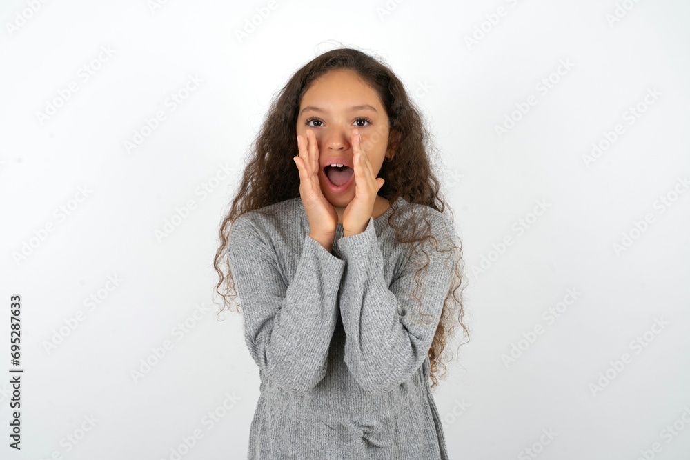 Beautiful teen girl wearing grey dress over white background shouting excited to front. Beautiful teen girl wearing grey dress over white background shouting excited to front.