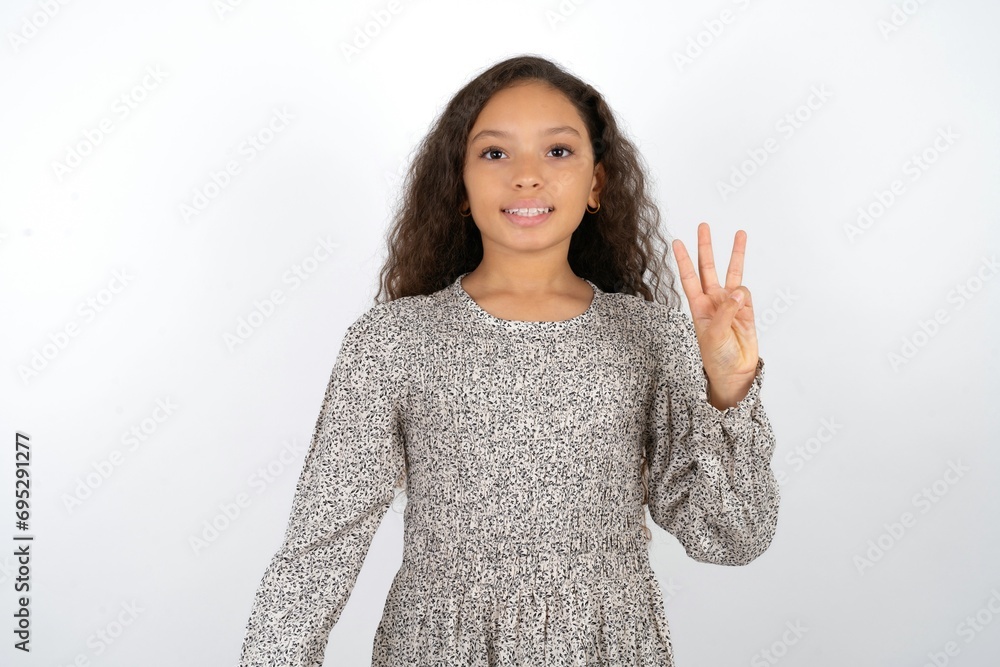 Beautiful teen girl wearing grey dress over white background showing and pointing up with fingers number three while smiling confident and happy. Beautiful teen girl wearing grey dress over white background showing and pointing up with fingers number three while smiling confident and happy.