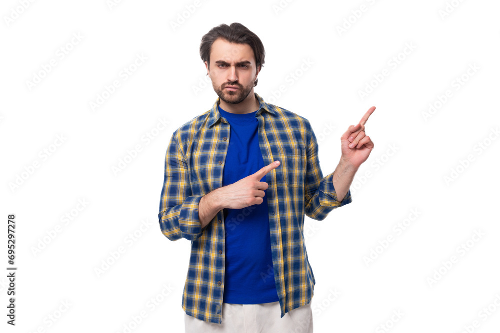 a well-groomed brunette brutal man with a beard in a plaid shirt holds his hand pointing to the side for space for news a well-groomed brunette brutal man with a beard in a plaid shirt holds his hand pointing to the side for space for news