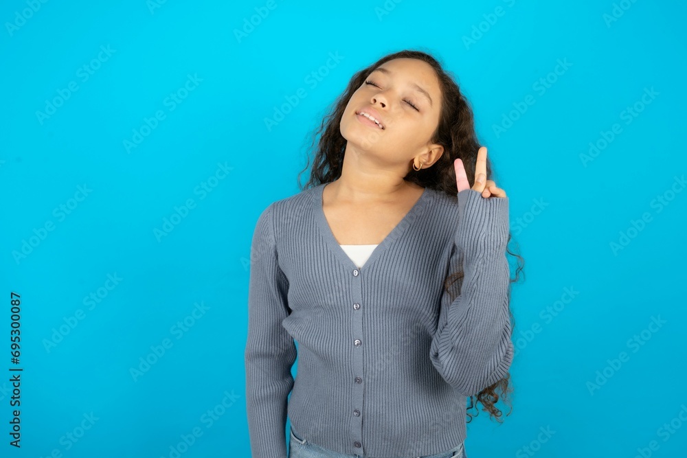 Beautiful teen gil wearing casaul clothes over blue background smiling with happy face winking at the camera doing victory sign. Number two. Beautiful teen gil wearing casaul clothes over blue background smiling with happy face winking at the camera doing victory sign. Number two.