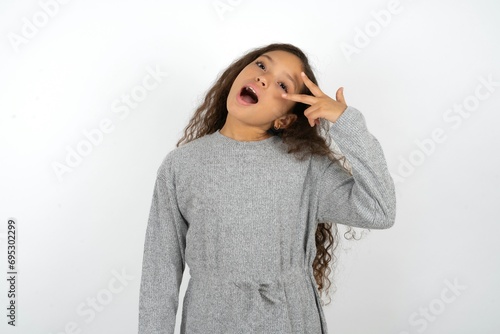 Beautiful teenager girl Doing peace symbol with fingers over face, smiling cheerful showing victory