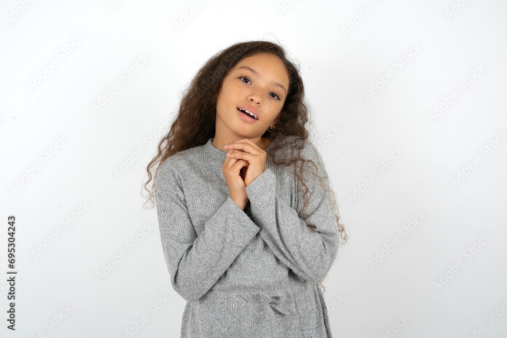 Positive Beautiful teenager girl smiles happily, glad to receive pleasant news from interlocutor, keeps hands together. People emotions concept. Positive Beautiful teenager girl smiles happily, glad to receive pleasant news from interlocutor, keeps hands together. People emotions concept.