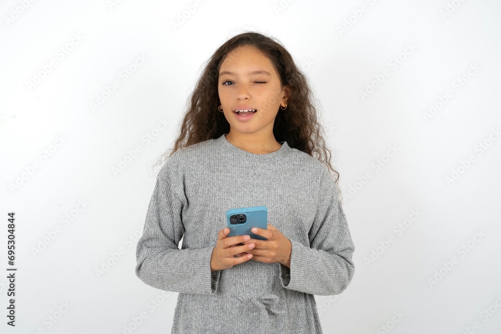 Excited Beautiful teenager girl winking and eye hold smart phone use read social network news Excited Beautiful teenager girl winking and eye hold smart phone use read social network news