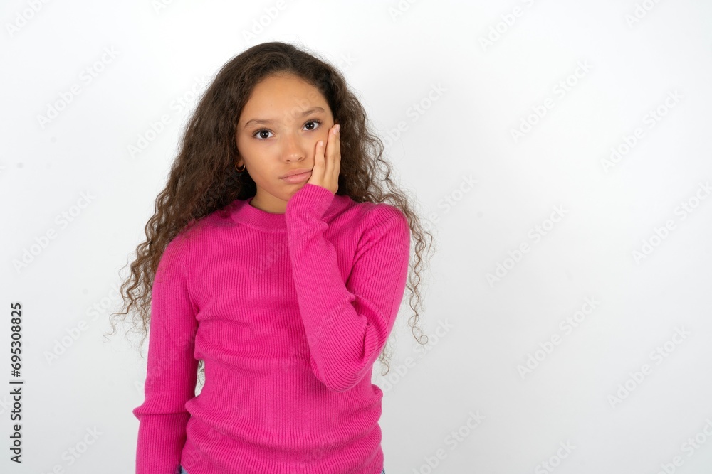 Sad lonely Young beautiful teen girl touches cheek with hand bites lower lip and gazes with displeasure. Bad emotions Sad lonely Young beautiful teen girl touches cheek with hand bites lower lip and gazes with displeasure. Bad emotions