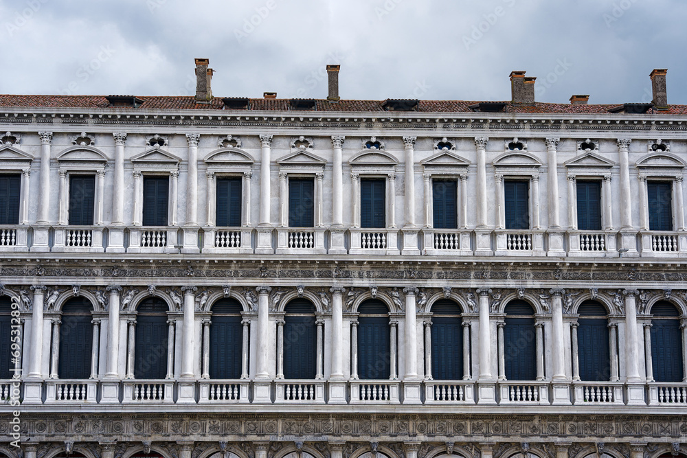 Close-up of white stone facade of historic building at Piazza San Marco square at City of Venice on a blue cloudy summer day. Photo taken August 6th, 2023, Venice, Italy.