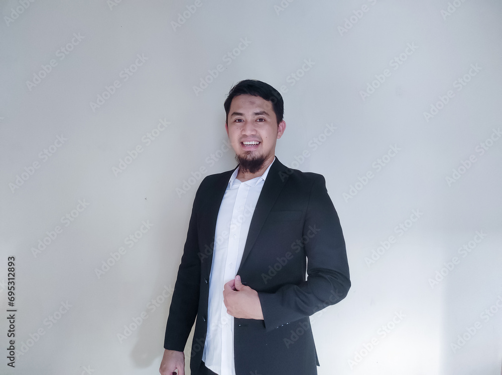 Asian businessman clenches his fist showing excitement while looking at the cell phone he is holding Asian businessman clenches his fist showing excitement while looking at the cell phone he is holding