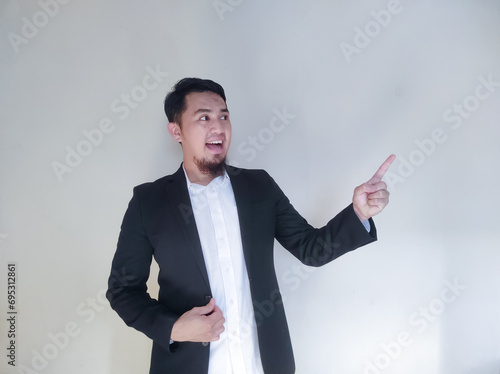 Asian businessman expresses joy and excitement while pointing at the empty area around him photo