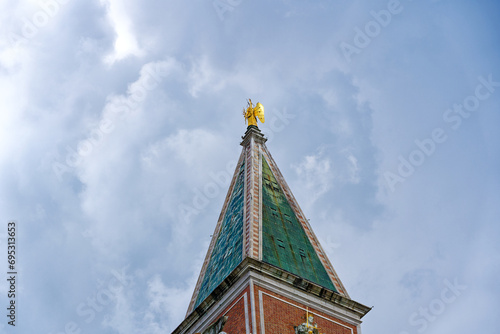 Piazza San Marco with top of Campanile di San Marco with golden angel on top at City of Venice on a cloudy summer day. Photo taken August 6th, 2023, Venice, Italy. photo