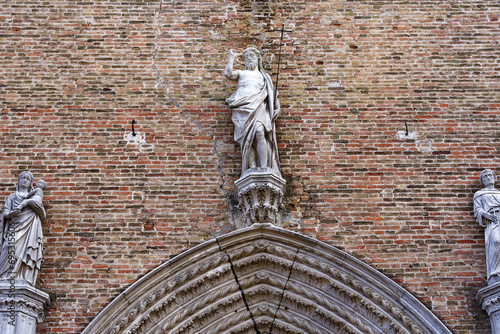 Close-up of brick wall with statue of Jesus Christ at entrance of church Santa Maria Gloriosa dei Frari at City of Venice on a cloudy summer day. Photo taken August 6th, 2023, Venice, Italy. photo