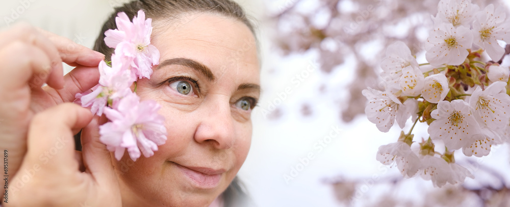 Obraz premium close up female face in flowers, small wrinkles around eyes, human eyes looking to side, concept of beauty and cosmetic anti-aging procedures, vision examination, human health, plant pollen allergy