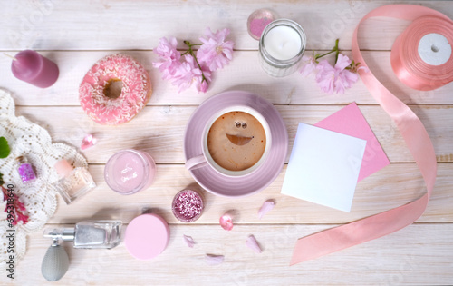 Coffee cup, donut, sakura flowers, aromatic candles, romantic little things on white wooden table, concept of Relaxation Haven in boudoir, female life