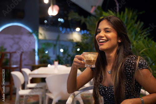 Mujer Joven latina  de cabello castaño largo tomando cafe sentada  photo