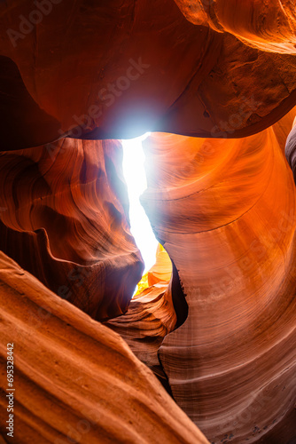 Image capturée dans le majestueux Antelope Canyon aux États-Unis, baignée d'une lumière orangée alors que les rayons du soleil filtrent à travers les fissures rocheuses.
