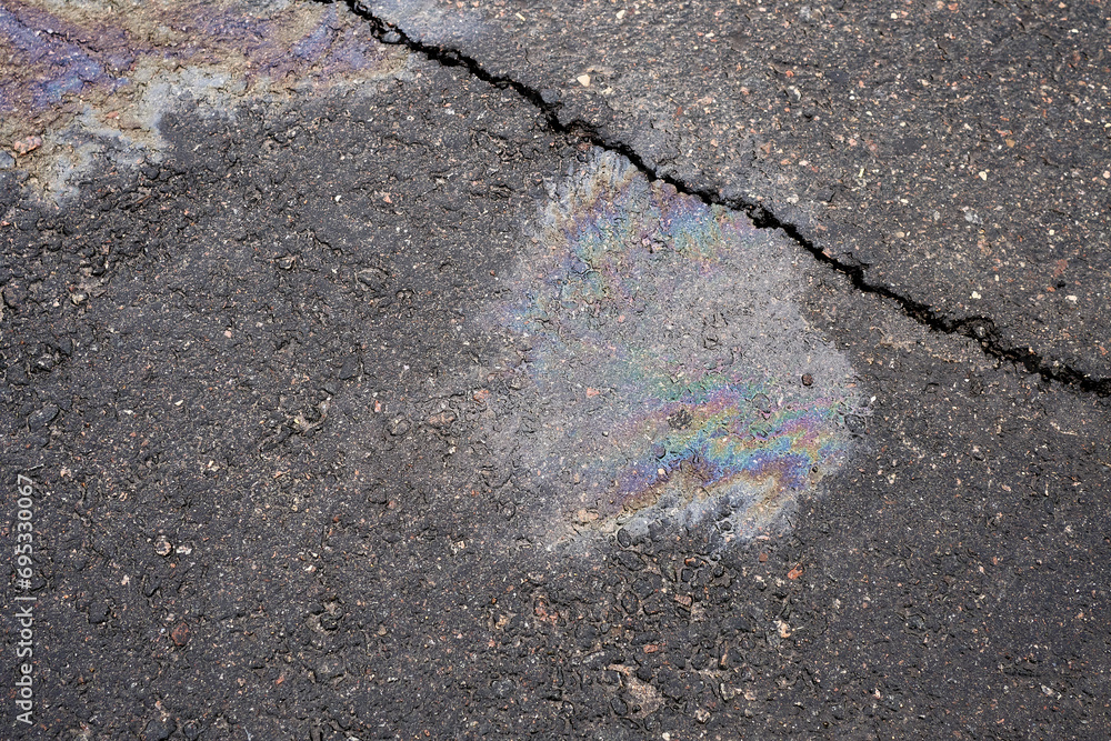 Obraz premium Leakage of oil or gasoline from the car on the asphalt in the parking lot. The concept of environmental pollution.