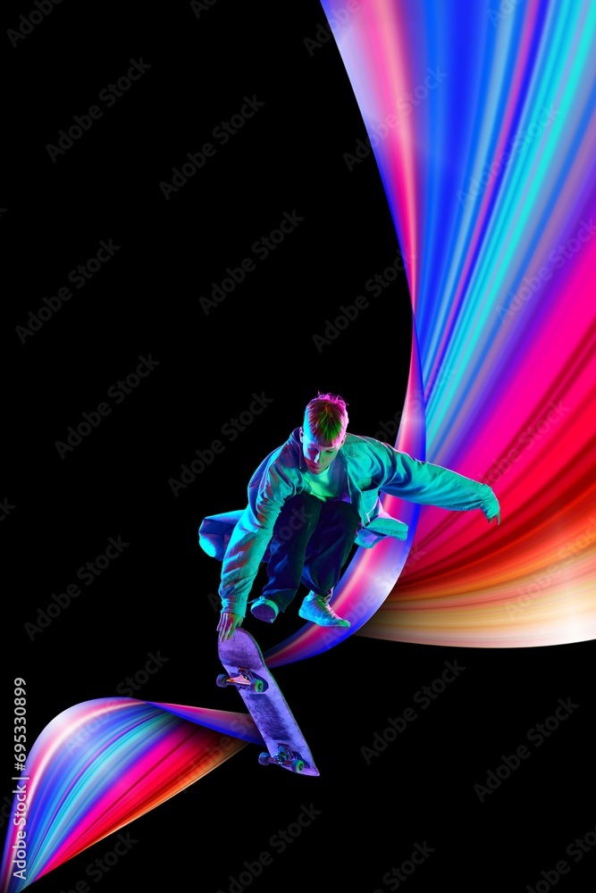 Obraz premium Young man, sportsman doing stunts on skateboard against black background in neon lights with colorful abstract element. Creative design. Concept of creativity, art, sport, competition, training