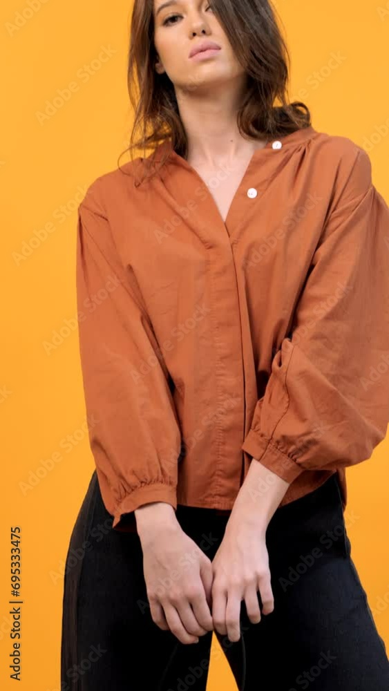 Stylish woman holding purse isolated on yellow background