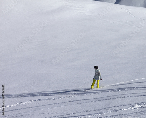 Snowboarder downhill on off piste slope with newly-fallen snow