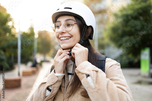 Smiling woman fastening helmet strap outdoors photo