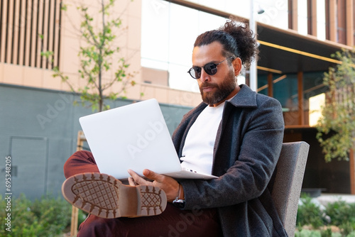 Stylish businessman working outdoors on a laptop photo