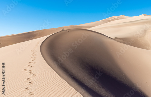 Silhouette of a tourist on the ridge of a large sand dune  Great Sand Dunes National Park  Preserve Colorado