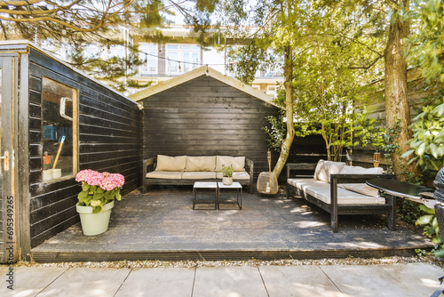 Sofa and table placed outside wooden shed in backyard photo
