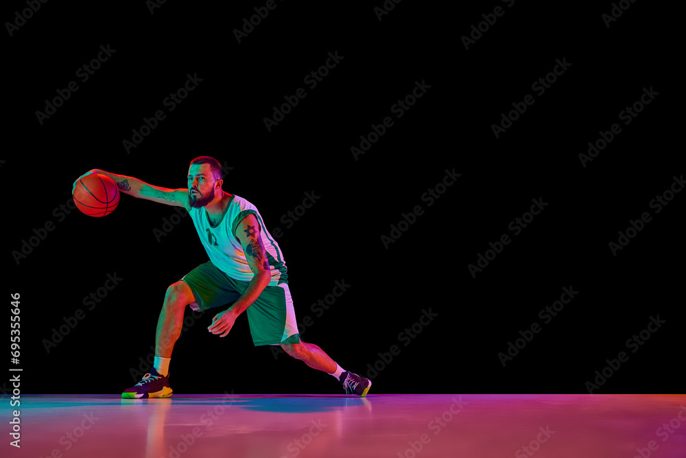 Basketball player workout in motion, highlighting dedication to perfecting craft against black background in mixed neon light.