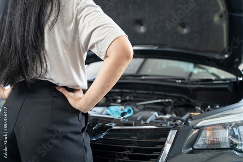 Asian woman having problems with her car Beautiful woman inspecting broken car before leaving home.