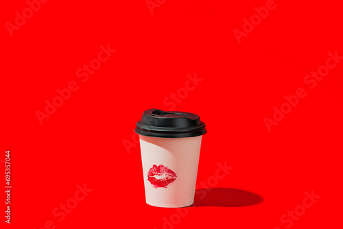 Disposable coffee cup with lipstick mark on red background