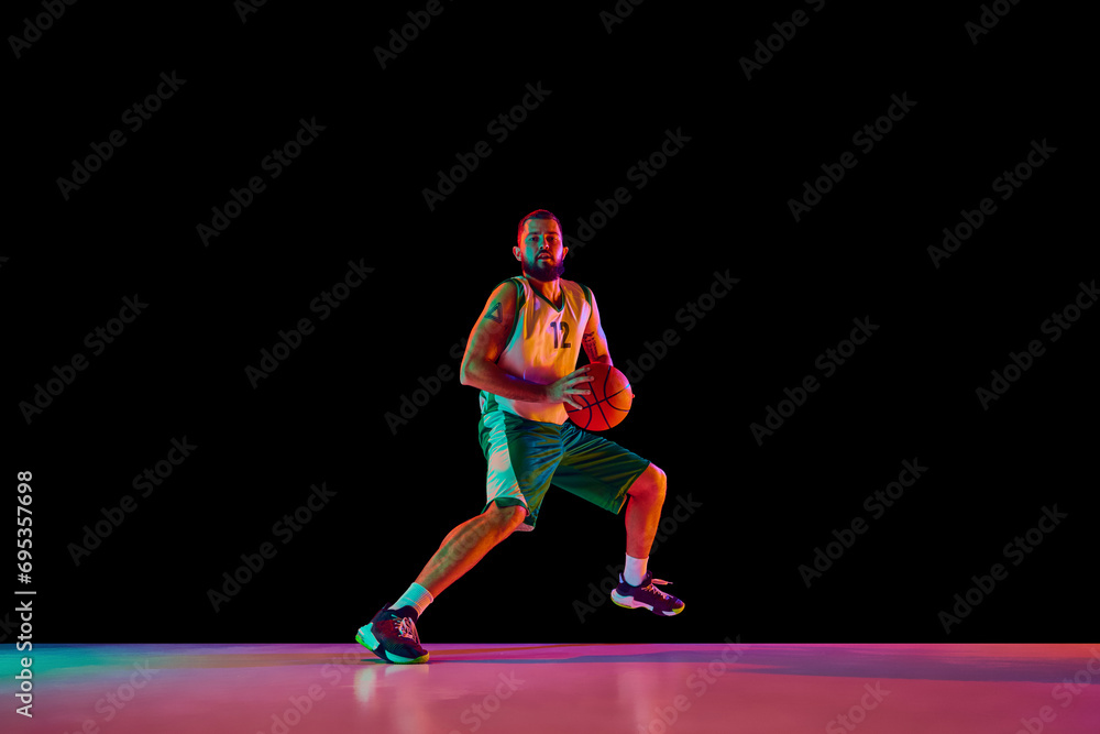 Basketball player, athletic man executing perfect slam dunk, illustration strength and precision against black background in neon light.