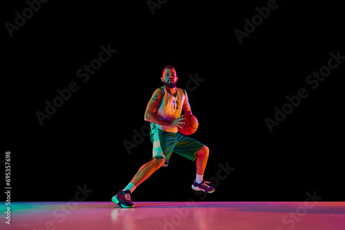 Basketball player, athletic man executing perfect slam dunk, illustration strength and precision against black background in neon light.