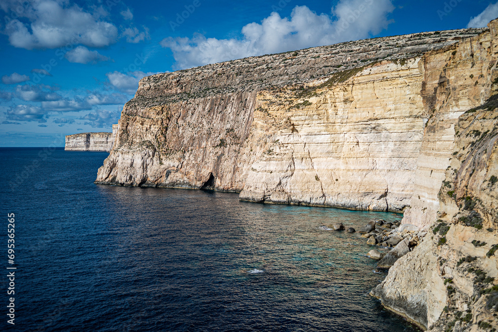 Cliffs and the sea in Gozo, summertime, blue sky with clouds, lunchtime, peace and silence Cliffs and the sea in Gozo, summertime, blue sky with clouds, lunchtime, peace and silence